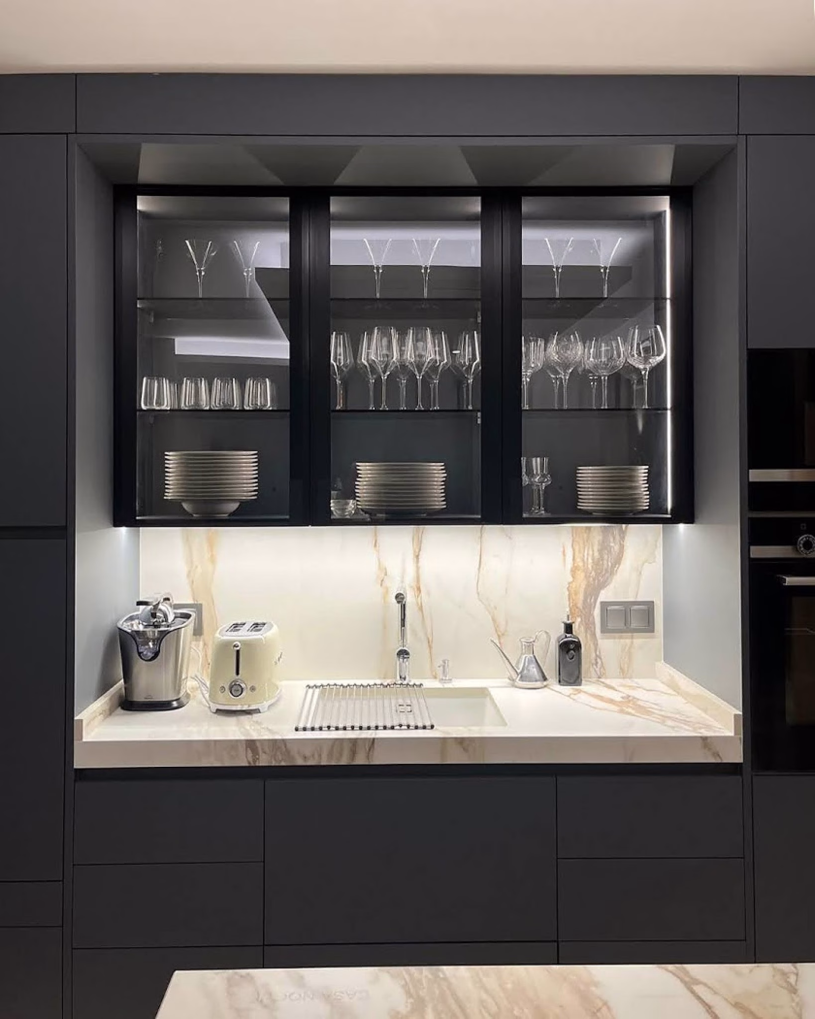 Cocina elegante con vitrina iluminada y encimera marmoleada