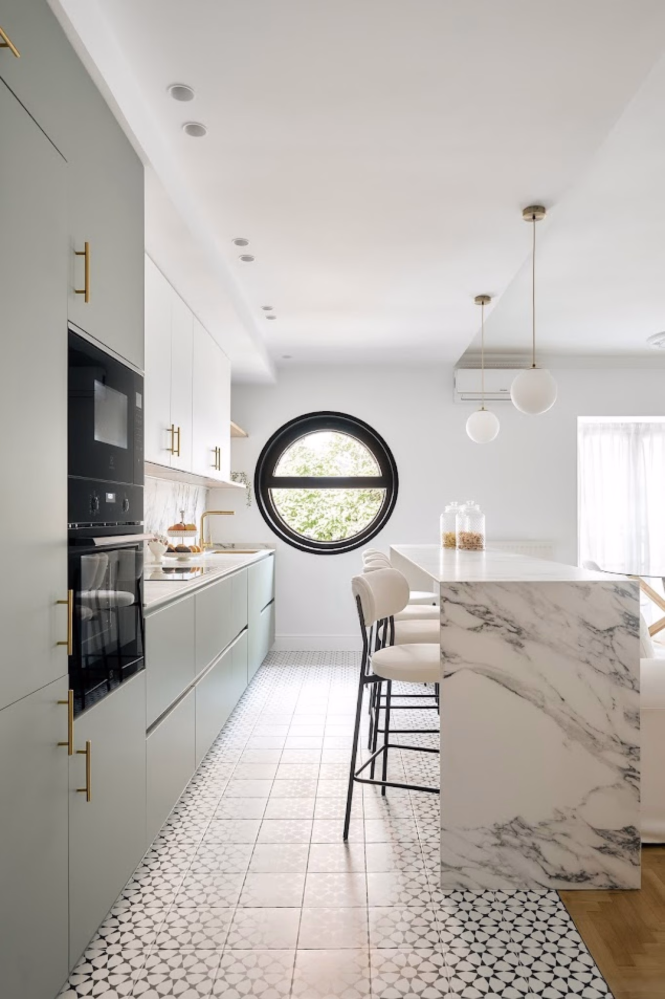 Cocina abierta con isla de mármol y muebles en tono verde suave