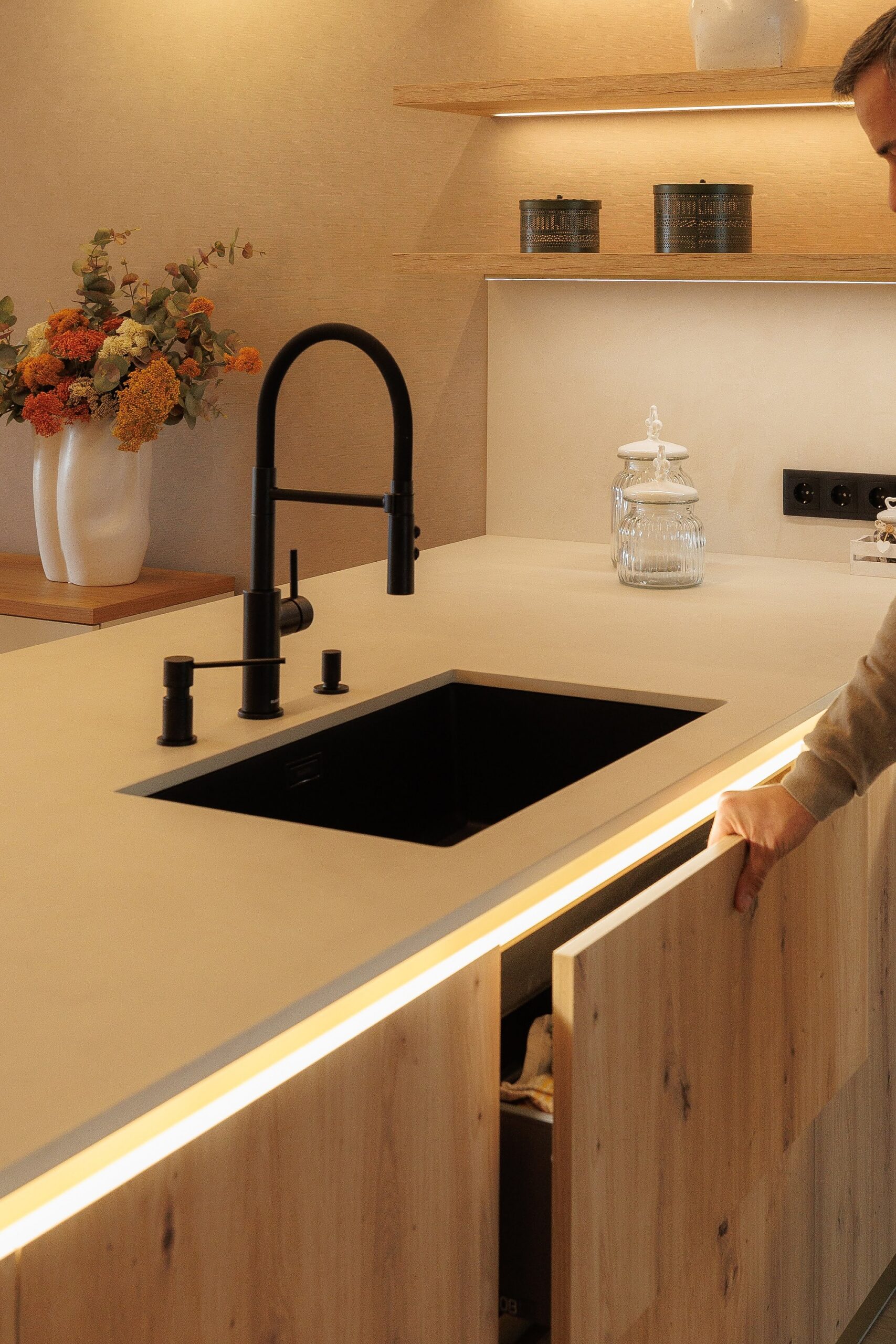 Cocina moderna con fregadero negro y grifo alto sobre encimera clara